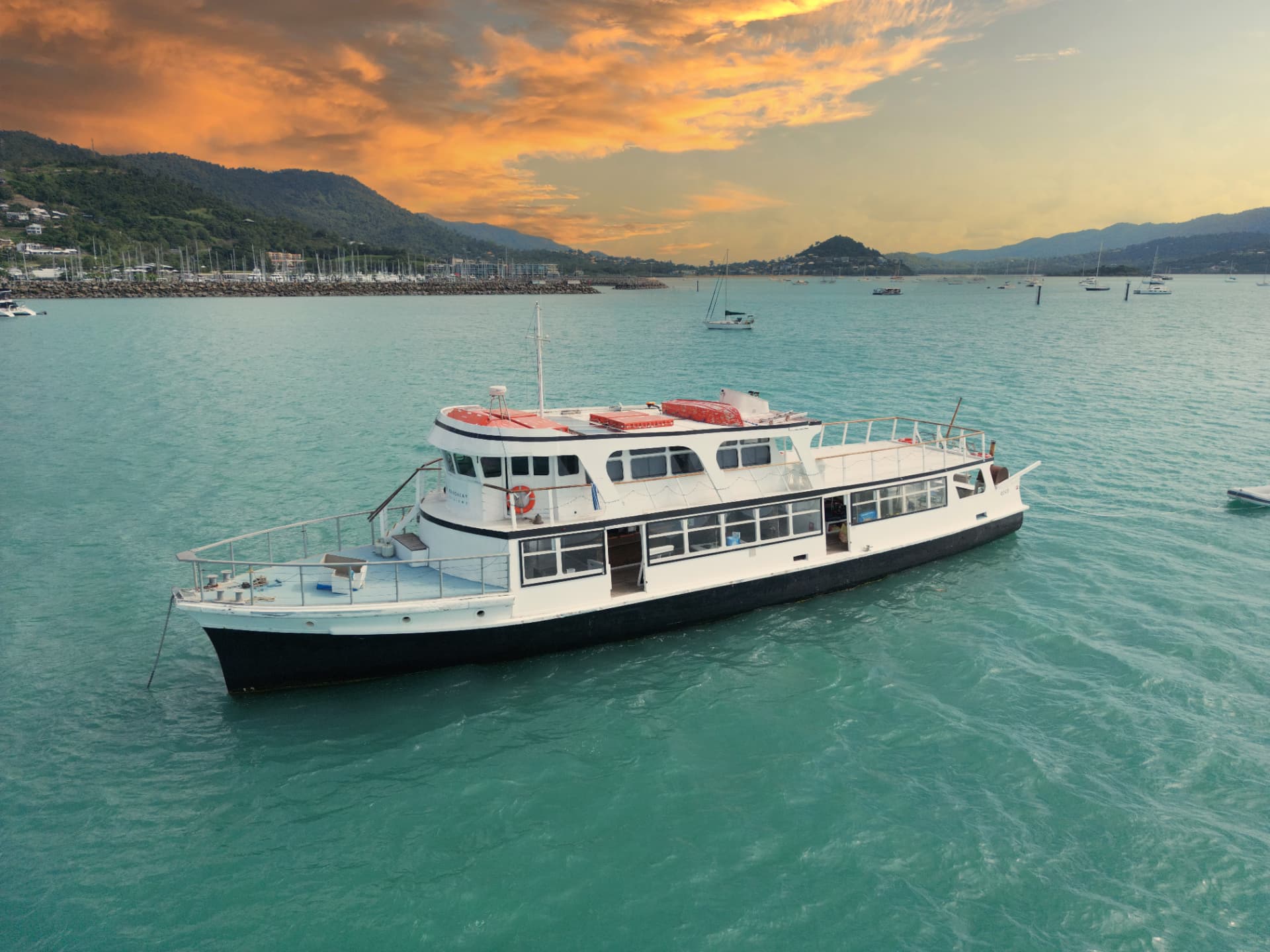 Luna Cruises vintage timber cruiser on turquoise water at sunset